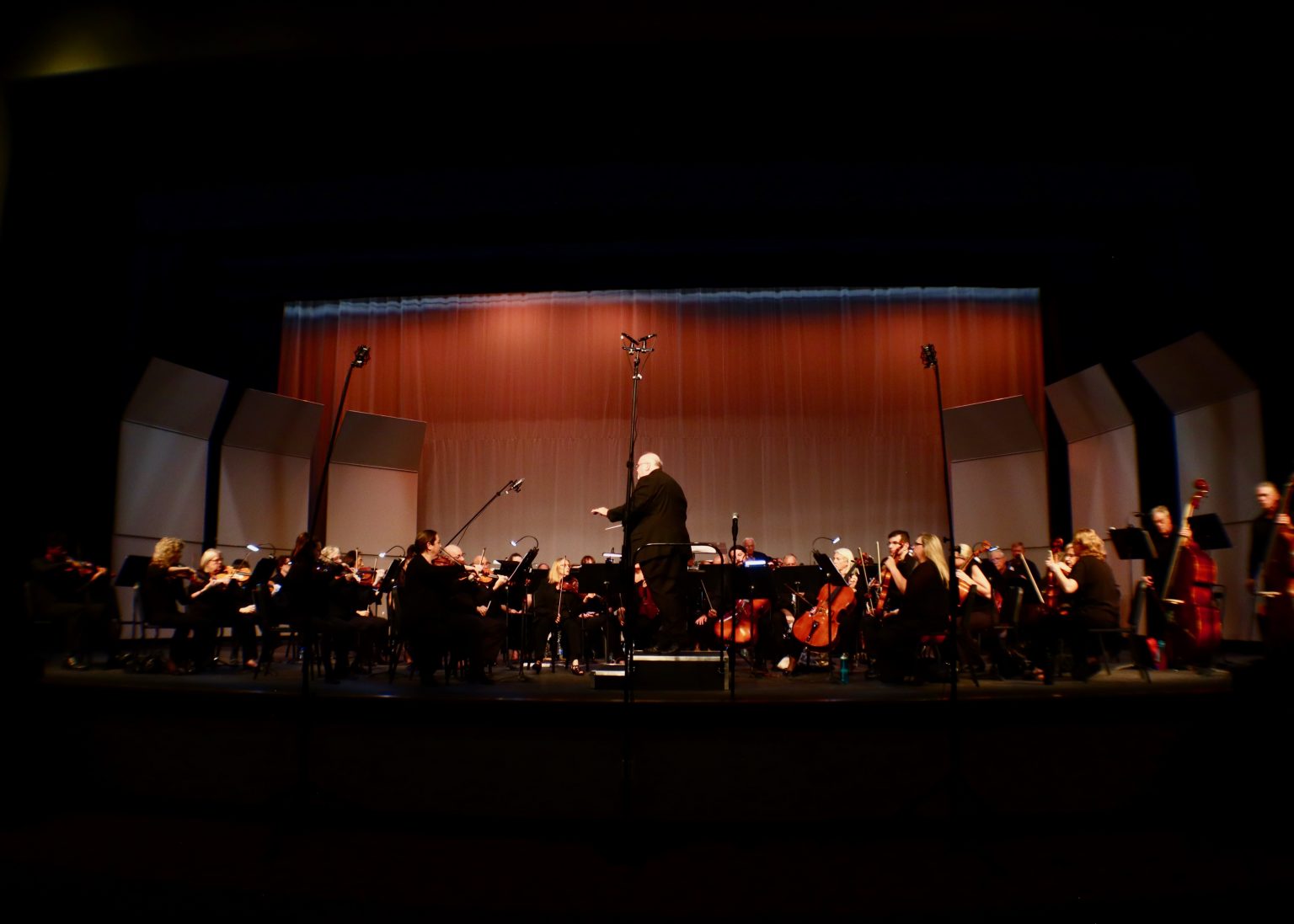 Gallery 1 - A full orchestra performs on a stage with warm lighting