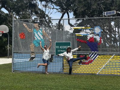 Local Artists pose in front of the fence mural project they created.