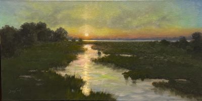 A beautiful scene of our own Guana Preserve at sundown, with the sparkle of sunlight reflecting on the gently moving water as the light softens to the muted greens and pinks of evening over sawgrass and scrub oaks. 